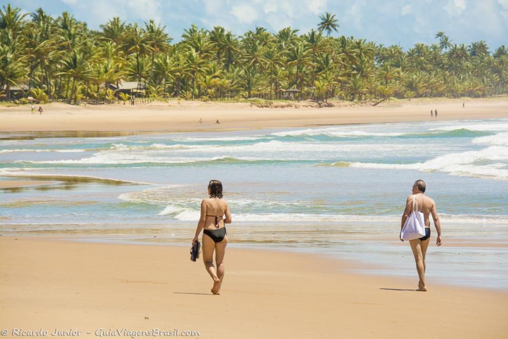 Imagem de casal caminhando na beira da Praia de Taipu de Fora.